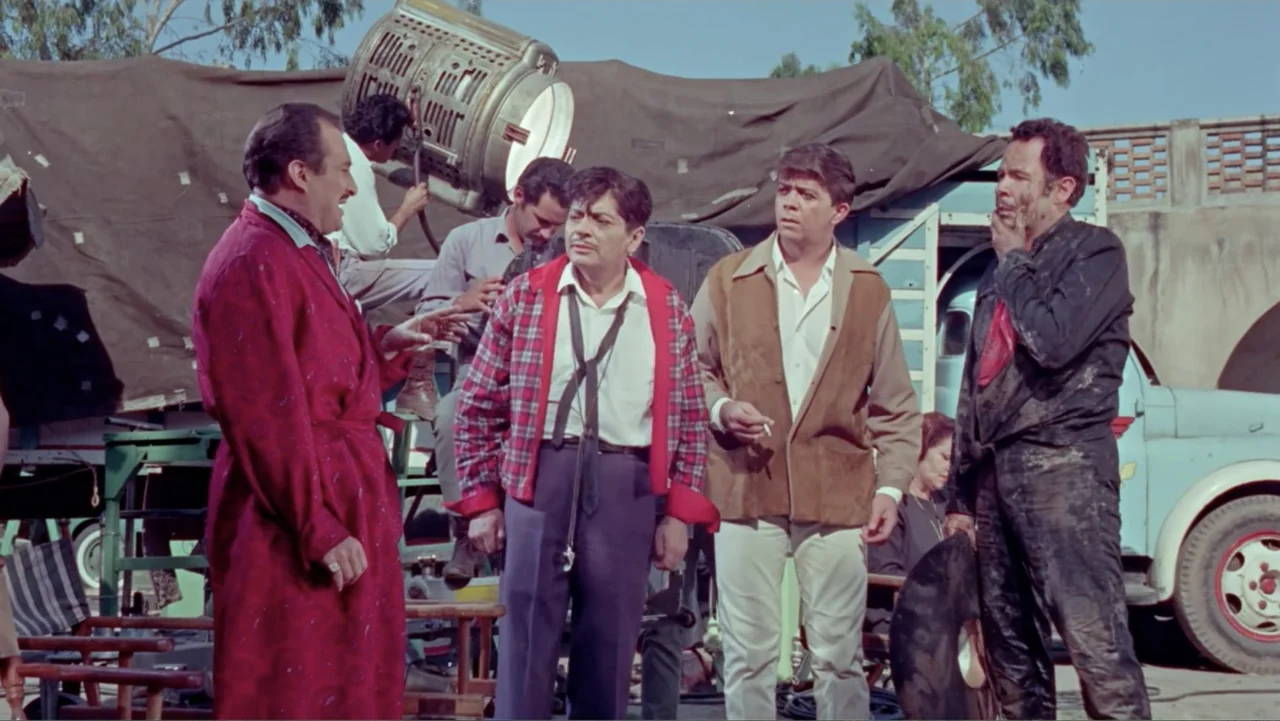Los Dos Rivales (1966) movie still: fullbody — A group of men stand on a dirt lot near a parked blue production truck. The men talk while facing…