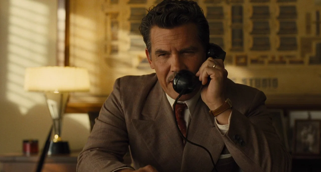 Hail, Caesar! (2016) movie still: medium — A mid-century office contains a desk with a rotary telephone and a table lamp. A man in a brown suit…