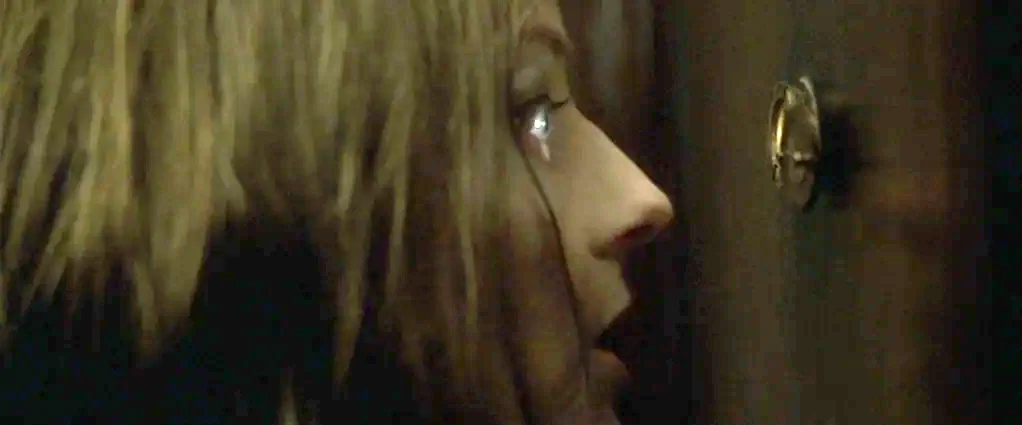 Panic Room (2002) movie still: closeup — A dark, wood-paneled apartment door features a small brass peephole in the center. A woman with damp hair…