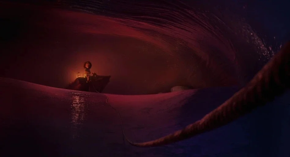 The Sea Beast (2022) movie still: wide — A small child sits inside a tiny boat within a vast, dark, cavernous space. A long rope trails from the…