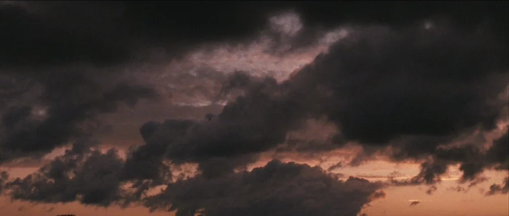 The Scouting Book for Boys (2009) movie still: establishing — Dense, dark storm clouds fill the frame against a fading sunset background. The lower…