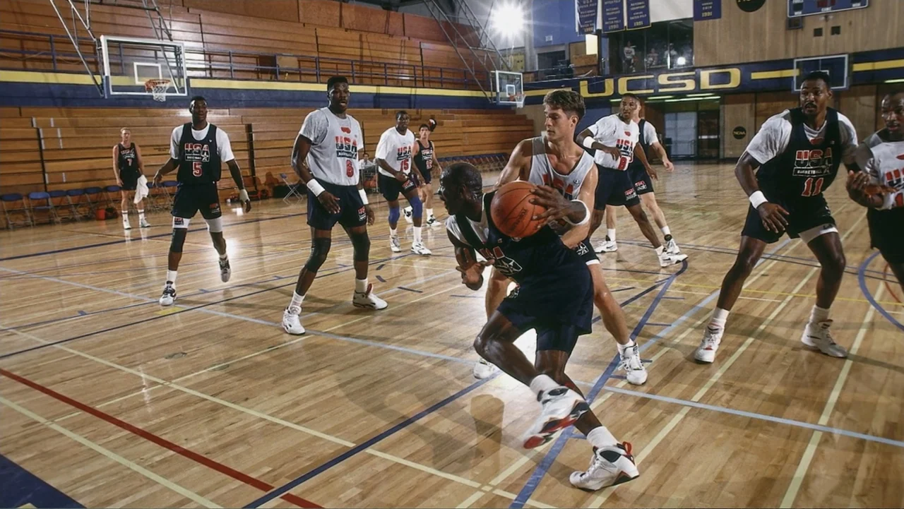 We Beat the Dream Team (2025) movie still: fullbody — A polished wooden basketball court inside a gymnasium features various players in team…