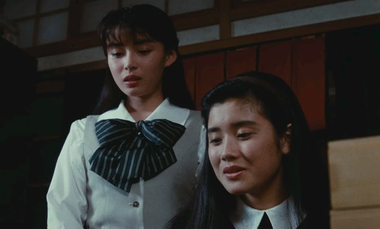Chizuko’s Younger Sister (1991) movie still: medium — Two young women stand together inside a room with traditional sliding wood panel screens. They…