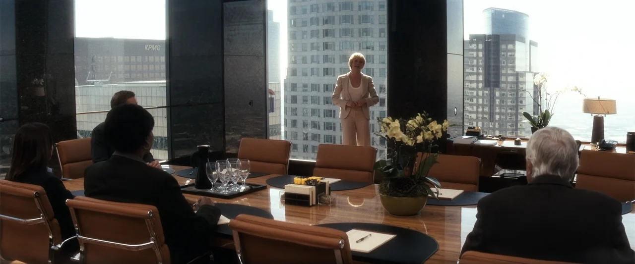 My Sister's Keeper (2023) movie still: wide — A high-rise boardroom features a polished wood table, leather chairs, and large window views. A woman…