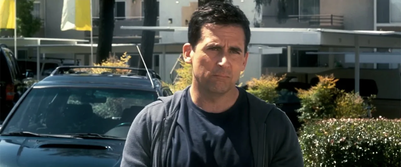 Crazy, Stupid, Love. (2011) movie still: medium — A sunny residential parking lot features asphalt and covered carports in the background. A man in…
