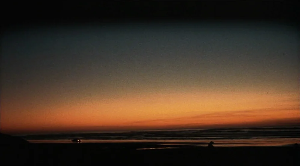 Five Easy Pieces (1970) movie still: establishing — A dark, expansive beach stretches out under a twilight sky with a colorful horizon. The…