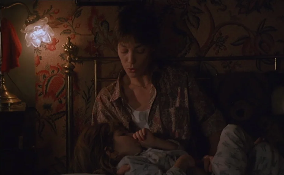 Kung Fu Master! (1988) movie still: medium — A bedroom at night featuring dark wallpaper with a large floral pattern. A woman sits on a bed with a…