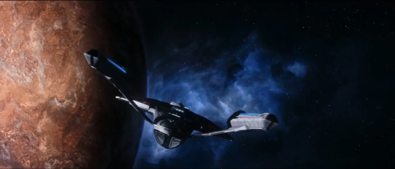 Star Trek: Nemesis (2002) movie still: wide — A dark, textured planet fills the left side of the frame in deep space. A starship moves toward the…