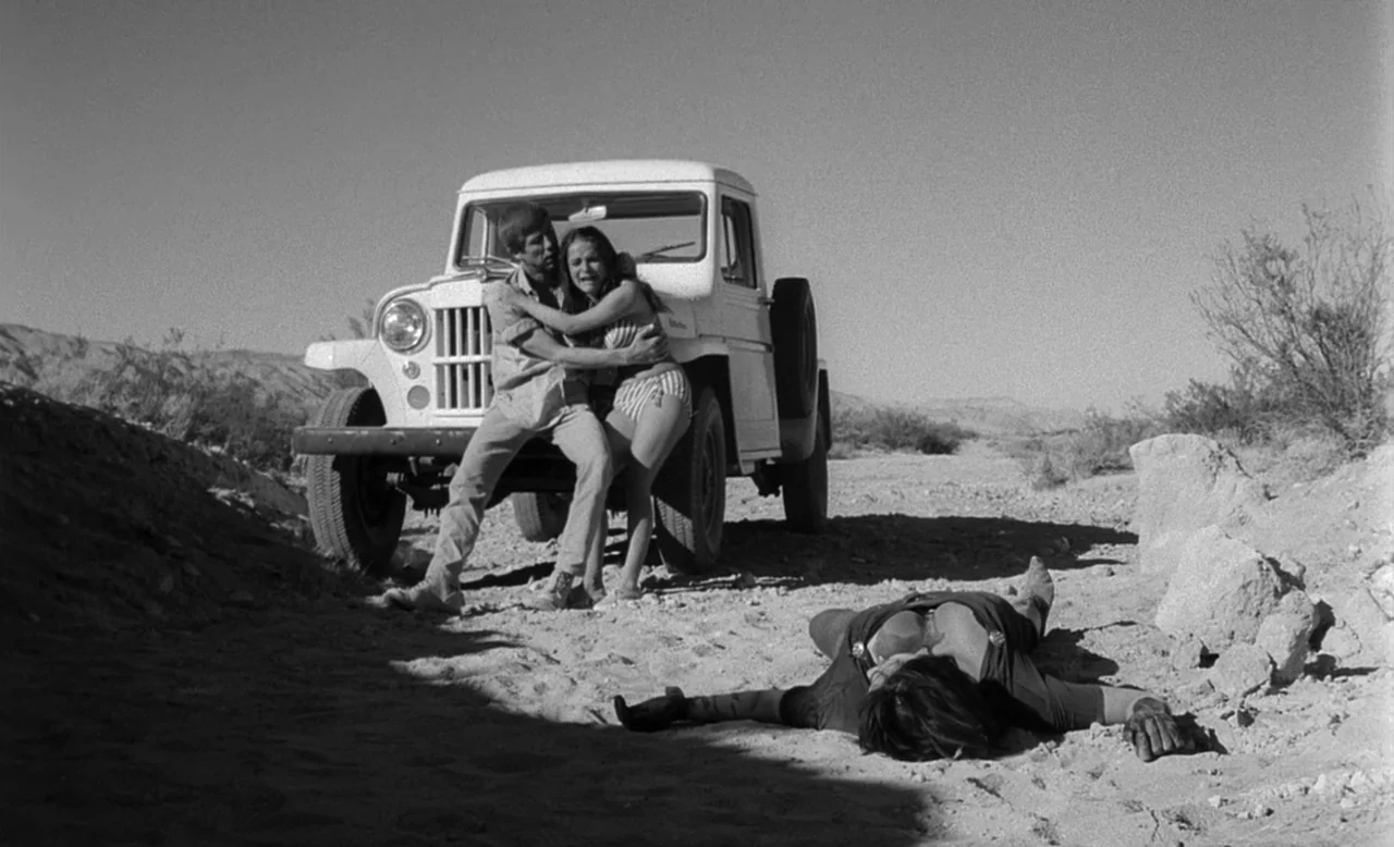 Faster, Pussycat! Kill! Kill! (1965) movie still: wide — A desolate desert track features a parked white Willys truck under bright sunlight. A man…