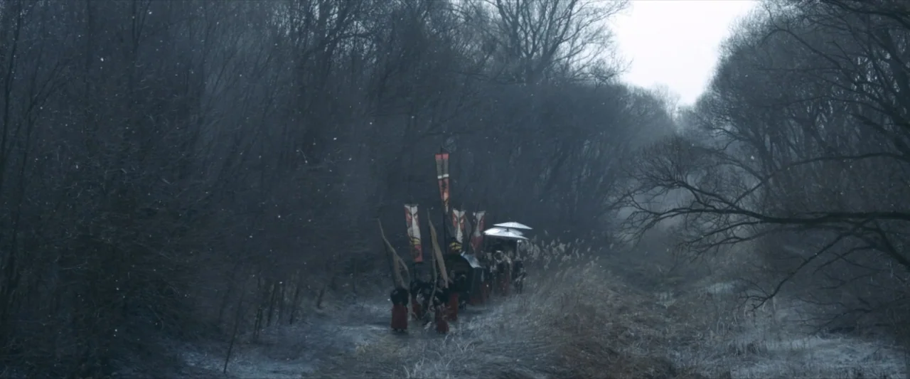47 Ronin (2013) movie still: wide — A group moves along a narrow path through a dense, leafless forest in winter. Multiple figures in traditional…