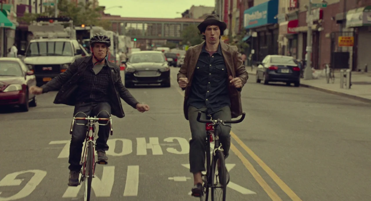 While We’re Young (2014) movie still: fullbody — A wide city street features painted school-zone markings on the asphalt and parked vehicles. Two…
