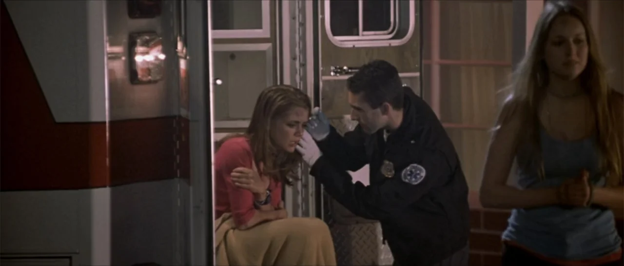 Joy Ride (2001) movie still: medium — An emergency medical vehicle exterior at night with an open rear door. A uniformed medic attends to a young…