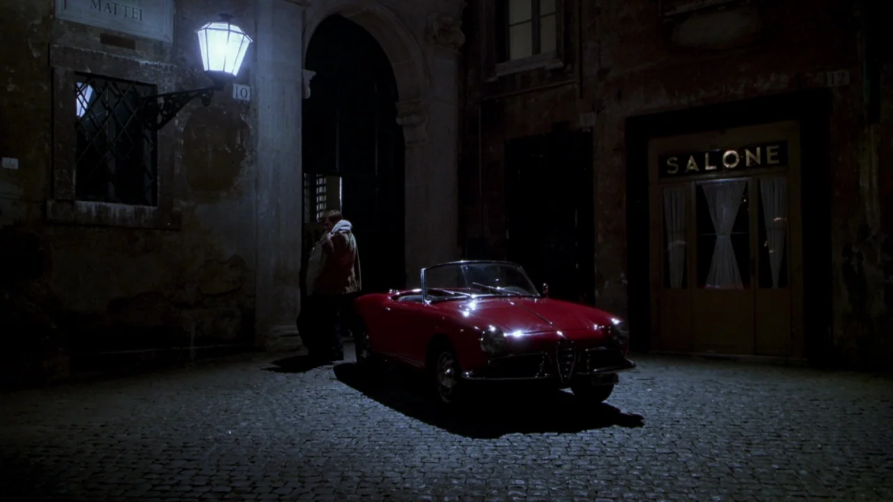 The Talented Mr. Ripley (1999) movie still: wide — A cobblestone urban alleyway features a bright red convertible parked under a glowing streetlamp.…