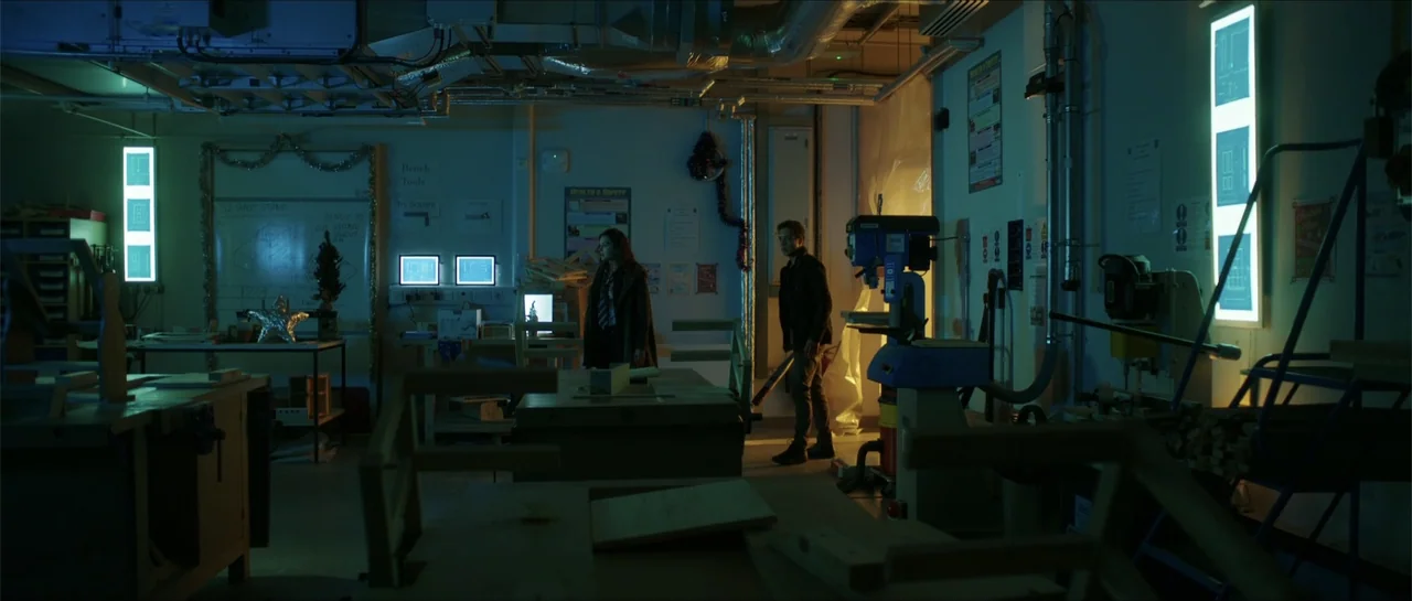 Anna and the Apocalypse (2018) movie still: wide — A dimly lit industrial school workshop features cluttered workbenches, metal tools, and exposed…