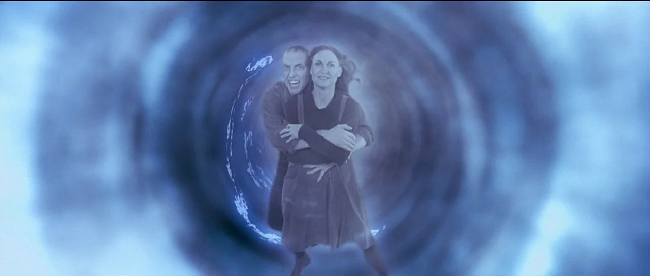 The Frighteners (1996) movie still: medium — Two individuals stand centered within a circular swirling blue vortex background. The man holds the…