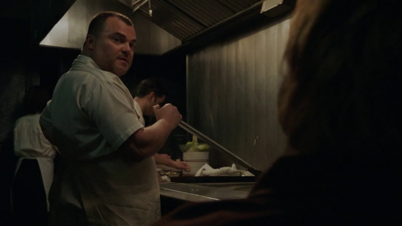 Don't Worry, He Won't Get Far on Foot (2018) movie still: medium — A dimly lit commercial kitchen features stainless steel equipment and an overhead…