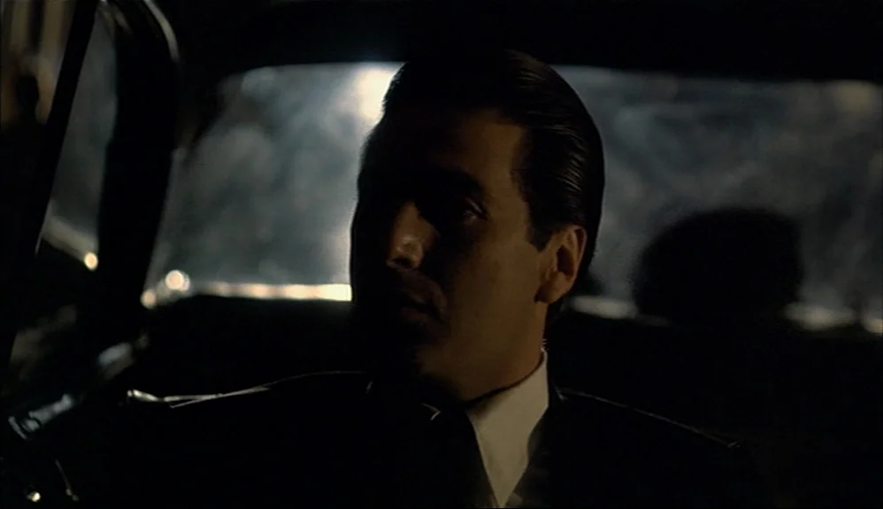 The Godfather Part II (1974) movie still: closeup — The interior of a vintage car at night provides a dark and confined space. A man in a dark suit…