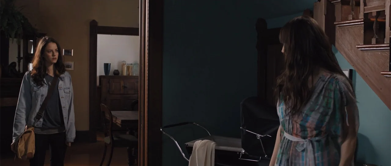 The Truth About Emanuel (2013) movie still: medium — A residential hallway connects to a dining room visible through an open doorframe. Two women…
