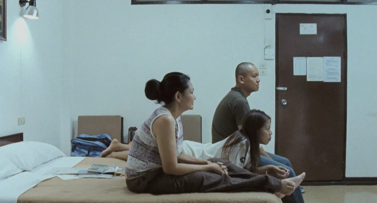 Uncle Boonme Who Can Recall His Past Lives (2010) movie still: medium — A spartan hotel room with white walls features a bed and a brown door. Three…