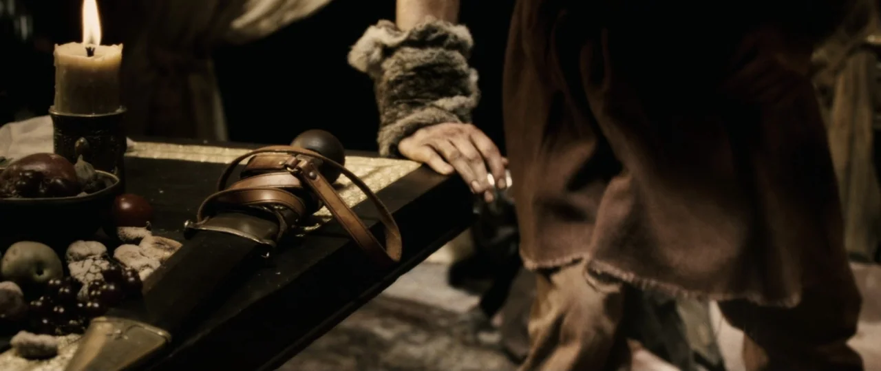 Centurion (2010) movie still: medium — A dark, wood-paneled room is illuminated by the flickering light of a single candle. A person wearing a fur…