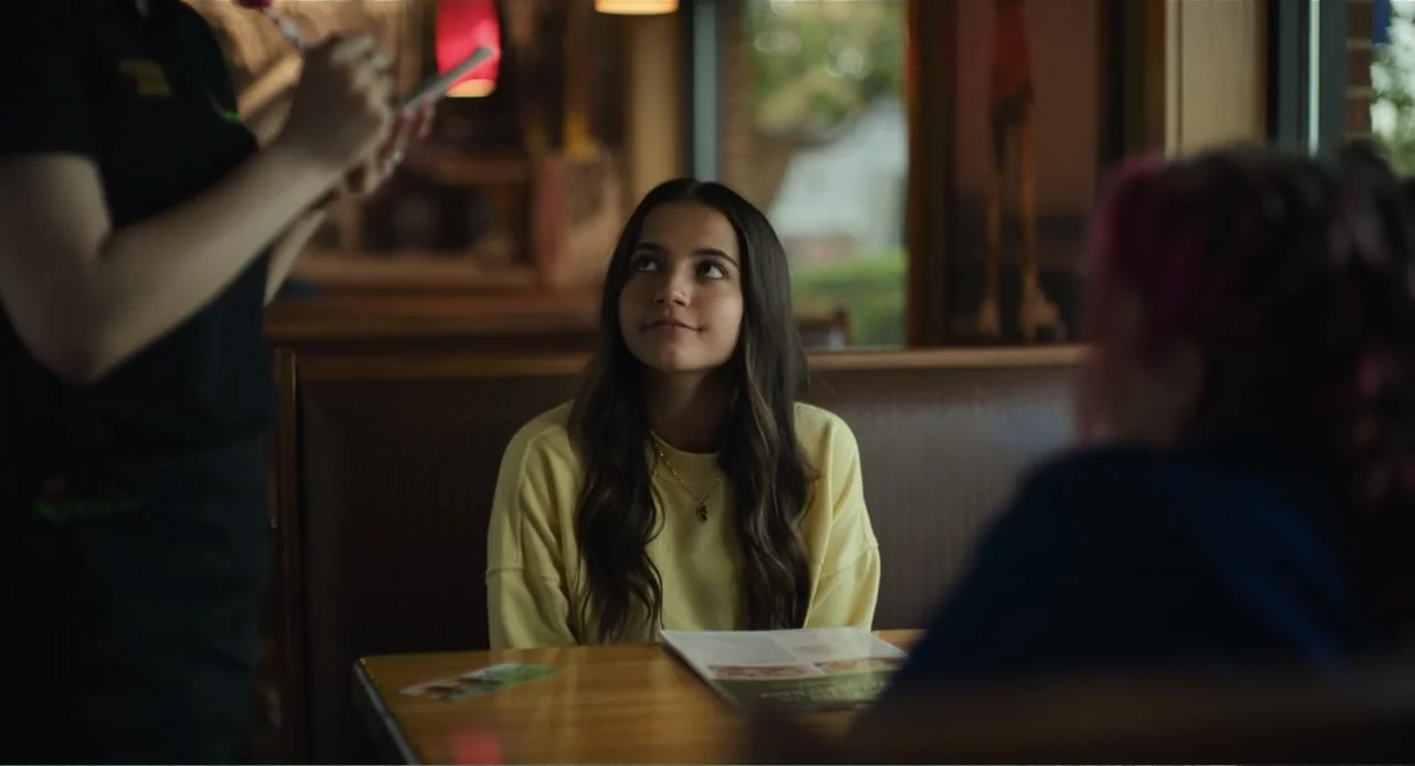 Turtles All the Way Down (2024) movie still: medium — A booth in a commercial diner features wooden trim and a laminated tabletop surface. A woman…