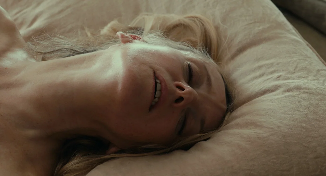 Last Summer (2023) movie still: closeup — A close-up view shows a person resting their head upon a soft beige pillow. The individual lies still with…