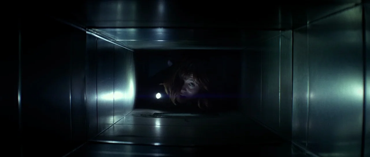 10 Cloverfield Lane (2016) movie still: medium — A narrow, rectangular metal ventilation duct stretches back into darkness. A woman crawls through…