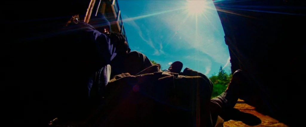 Hobo With A Shotgun (2011) movie still: wide — Two individuals sit inside a dark boxcar looking out into a bright sunny day. The train car opening…