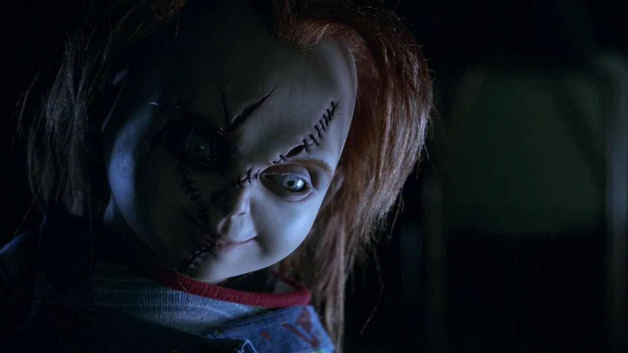 Curse of Chucky (2013) movie still: closeup — A close-up shot of a doll with visible surgical stitches on its face. The doll looks toward the camera…