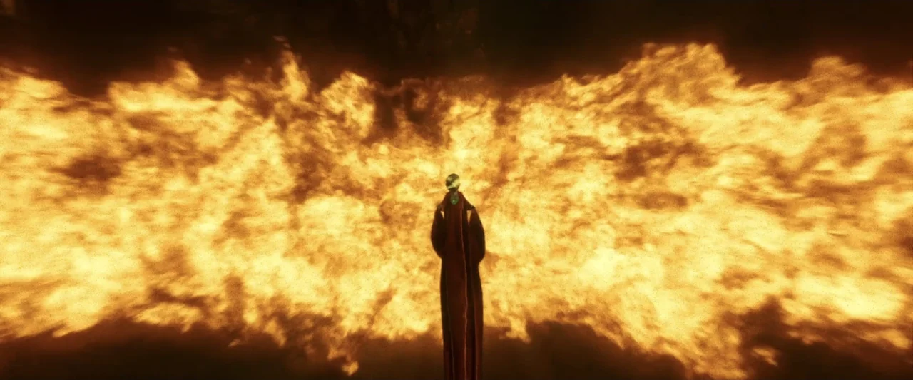 Green Lantern (2011) movie still: wide — A dark figure stands before a massive, wall-like eruption of bright orange flames. The fire fills the frame…