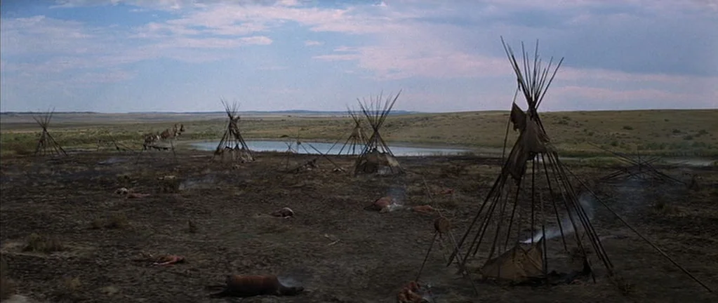 Little Big Man (1970) movie still: establishing — A scorched plains encampment features multiple tipis and a small pool under a cloudy sky. The…
