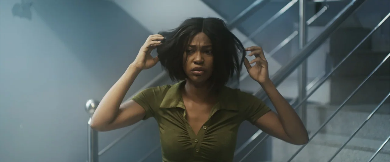 Casa De Novia (2024) movie still: medium — An interior stairwell features metal railings and grey tiled walls. A young woman in a green top stands…