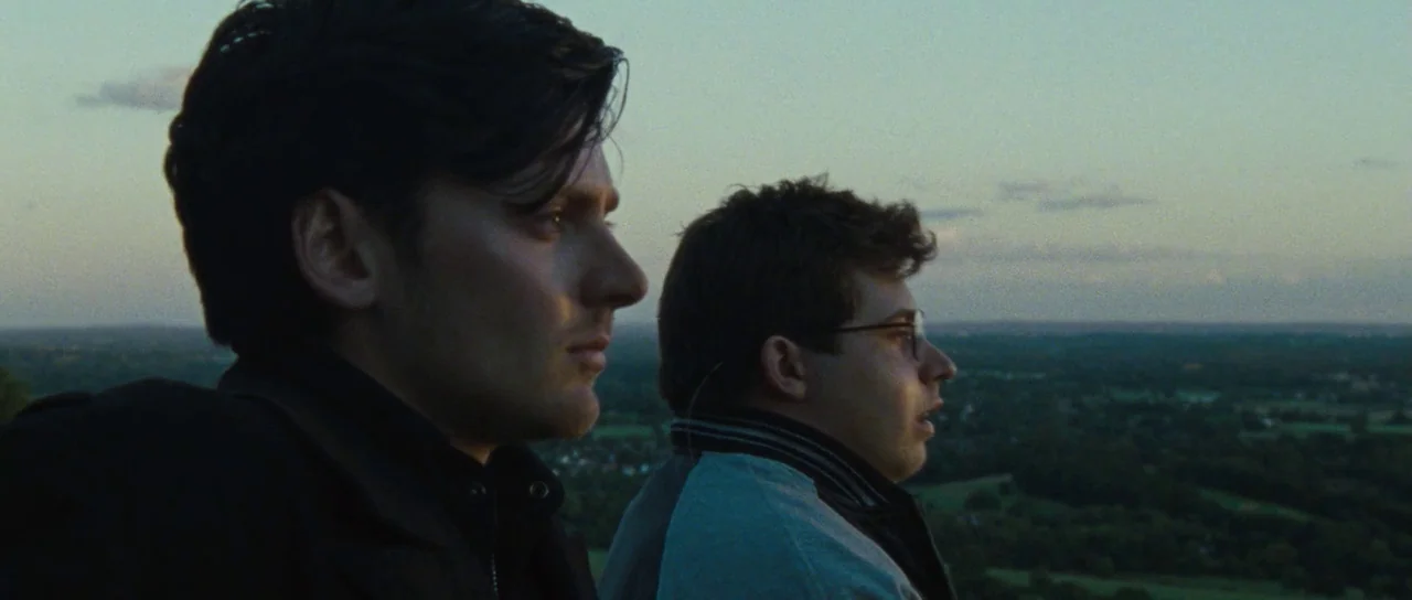 The World’s End (2013) movie still: medium — Two men stand on a grassy hilltop overlooking a vast landscape at twilight. The men stand in profile…