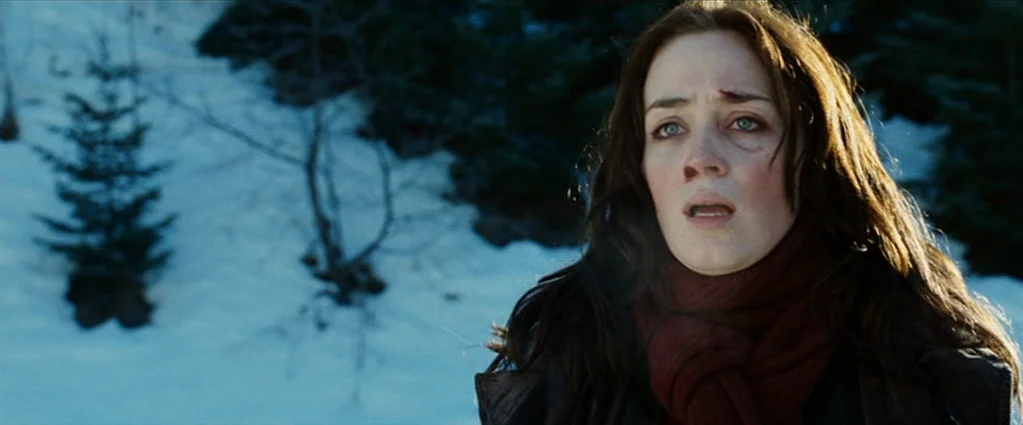 Wind Chill (2007) movie still: closeup — A snow-covered mountainside features sparse evergreen trees in the out-of-focus background. A woman in a…