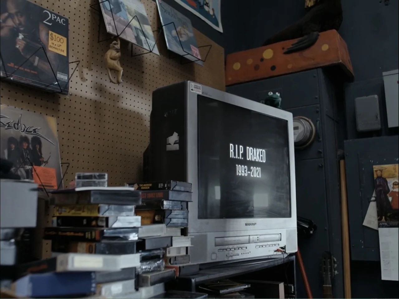 As We Speak: Rap Music on Trial (2024) movie still: medium — An cluttered interior space contains stacks of vintage media and a boxy television set.…