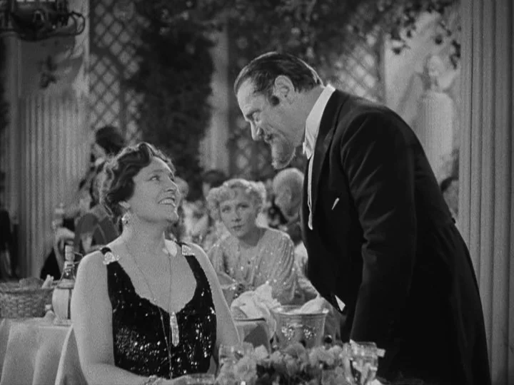 A Night at the Opera (1935) movie still: medium — An elegant dining room interior with lattice work walls and white tablecloths. A man in a formal…