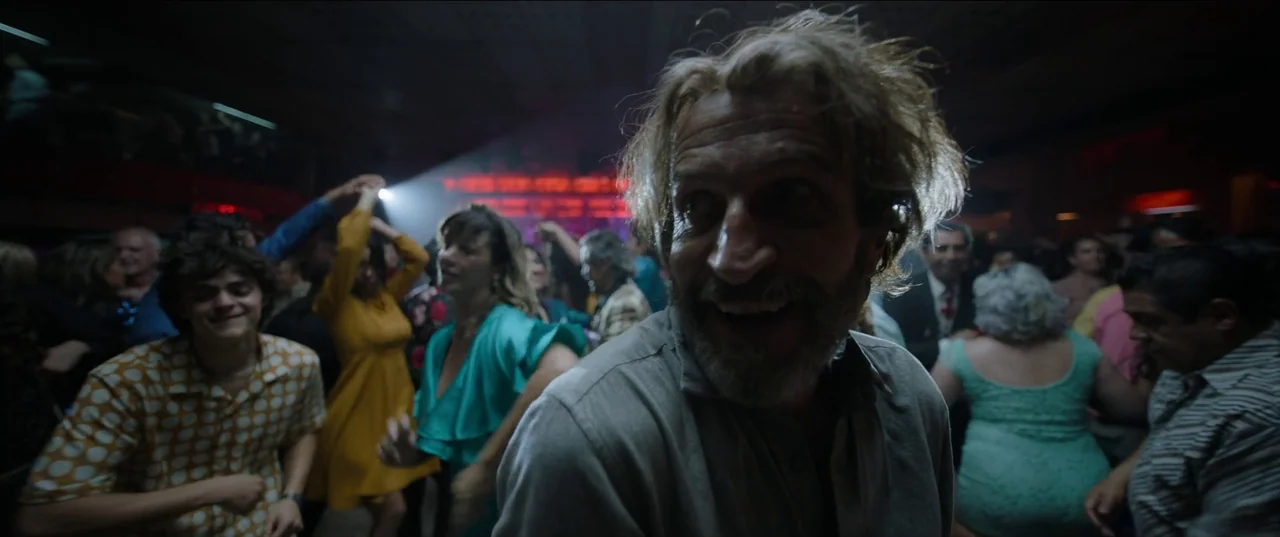 Bardo: False Chronicle of a Handful of Truths (2022) movie still: closeup — A crowded dance floor features people moving under low-key lighting and…