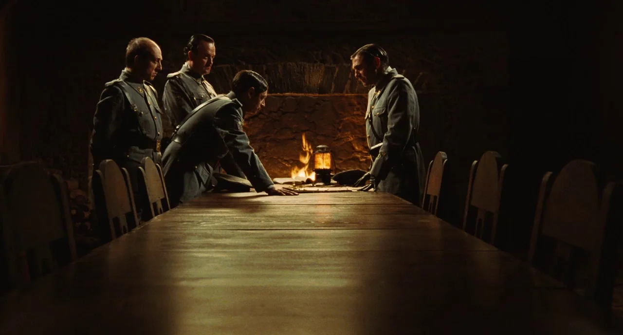 Pan’s Labyrinth (2006) movie still: wide — A stone-walled room features a long wooden table and an open stone fireplace. Four military officers in…