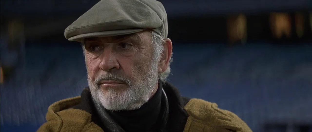 Finding Forrester (2000) movie still: closeup — An older man stands against the dark background of an empty, out-of-focus stadium. He gazes to the…