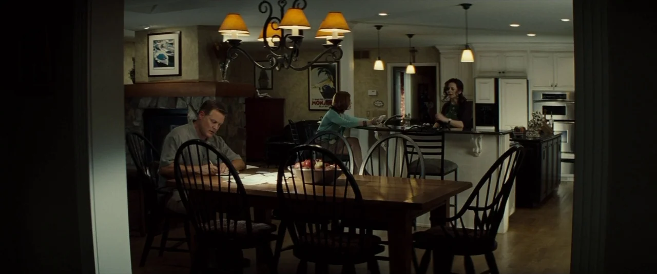 Gran Torino (2008) movie still: wide — A residential open-plan dining and food preparation area with wooden flooring and cabinetry. A man is seated…