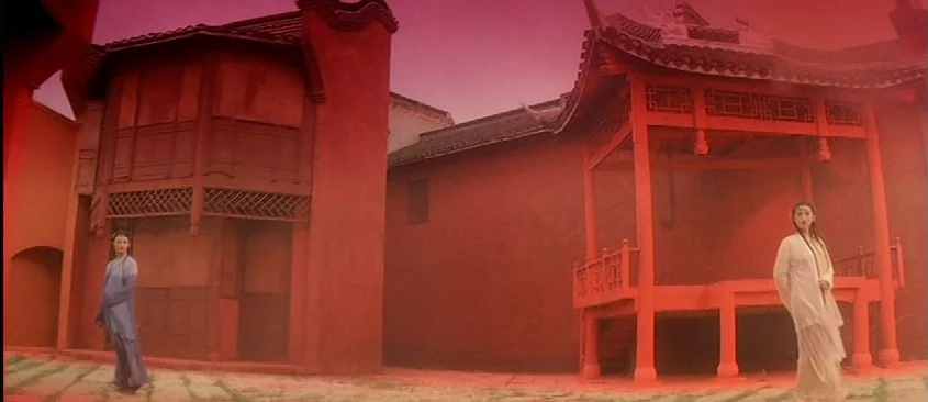 Green Snake (1993) movie still: wide — A traditional wooden pavilion structure stands in an outdoor area with stone paving. Two women stand on…