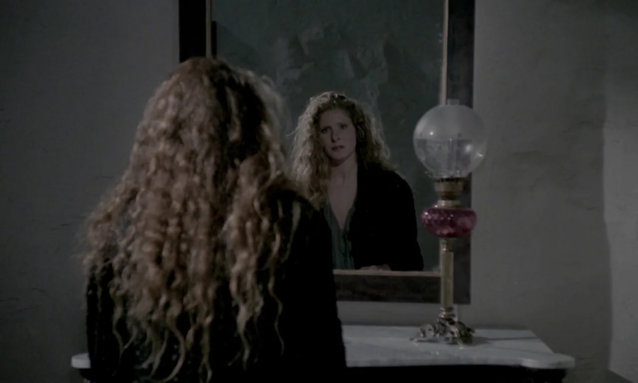 Nostalghia (1983) movie still: medium — A dimly lit room features a woman standing before a framed wall mirror. She gazes at her own reflection…