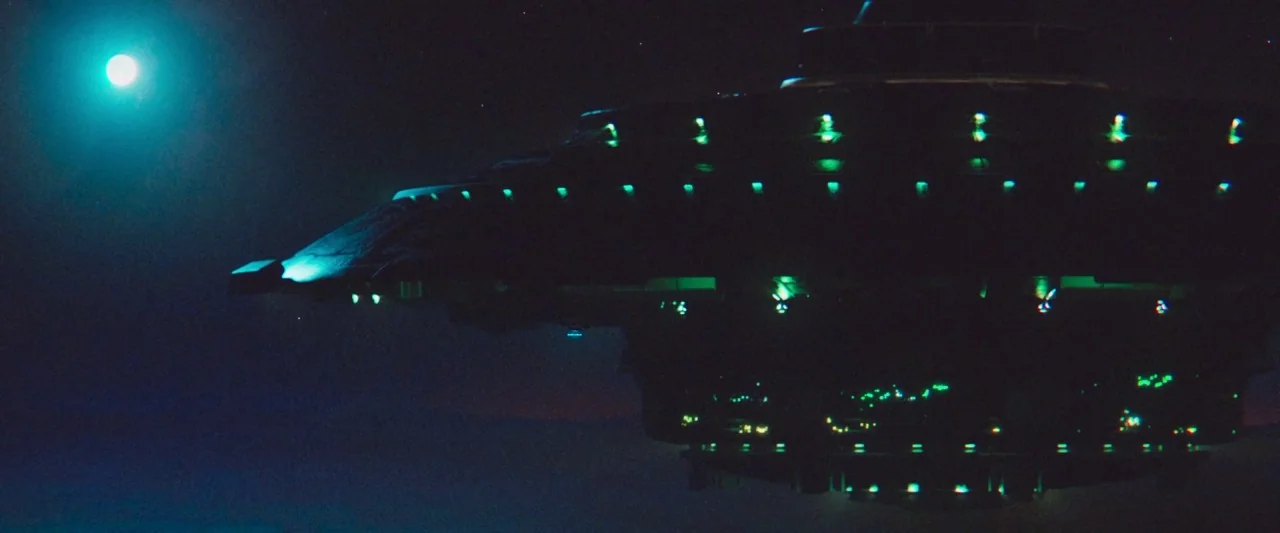 The Vast of Night (2019) movie still: wide — A massive, tiered metallic spacecraft floats against the dark expanse of the deep sky. Small glowing…