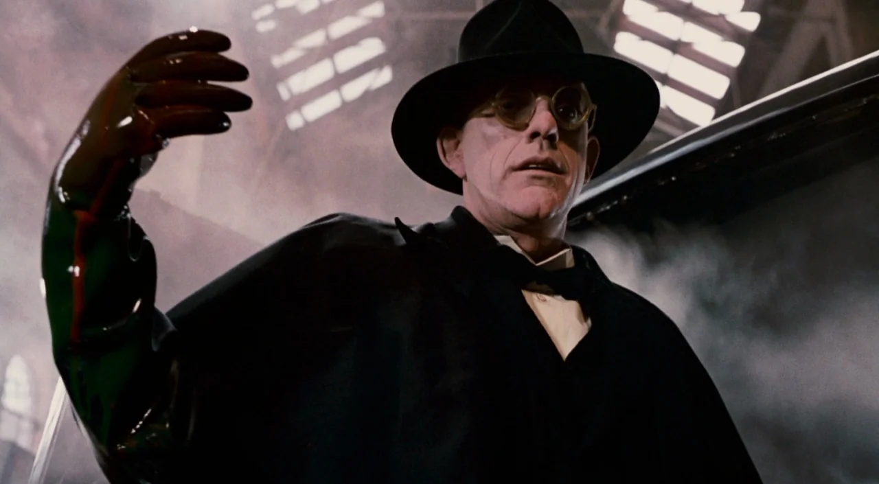 Who Framed Roger Rabbit (1988) movie still: medium — A dark industrial space filled with atmospheric smoke and metallic structural elements. A man…