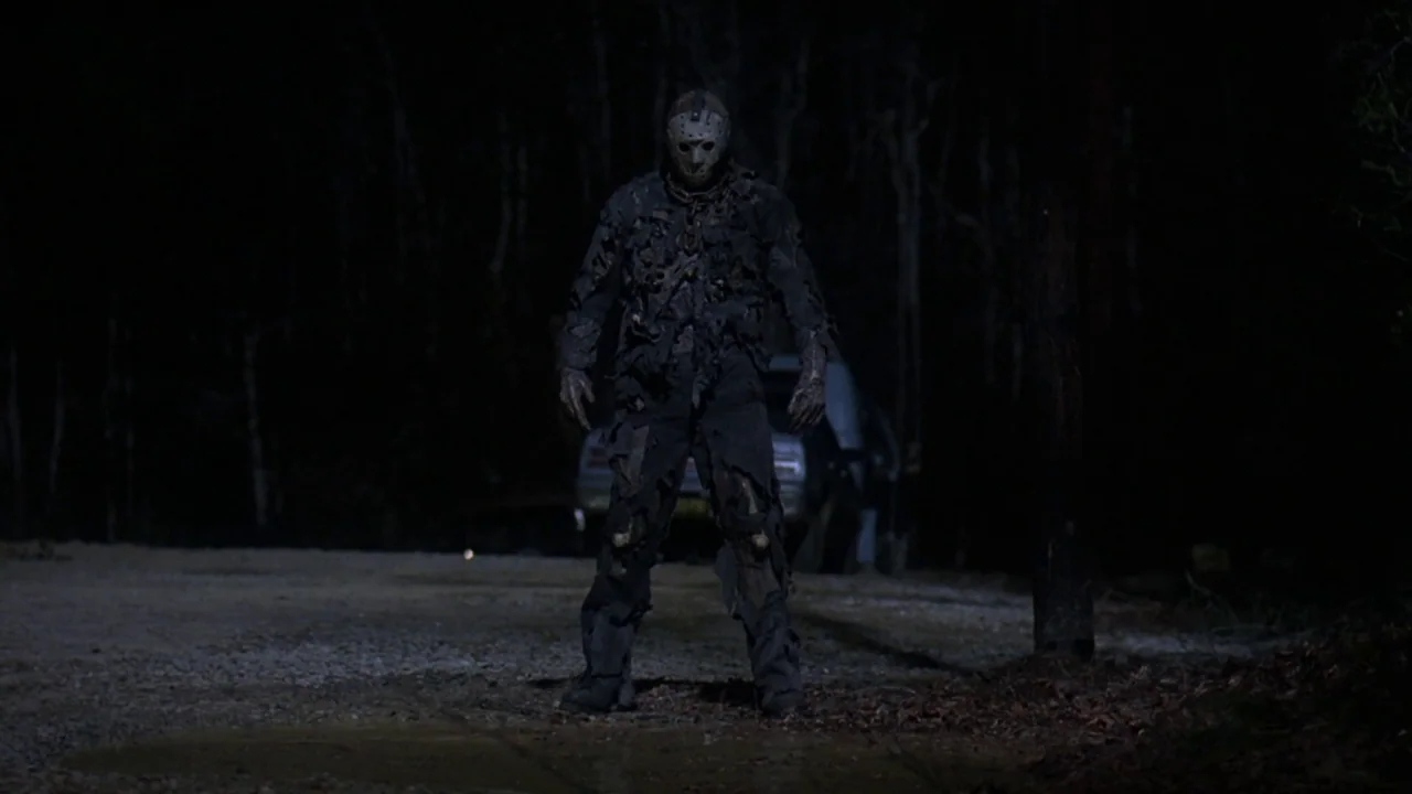 Friday the 13th Part VII: The New Blood (1988) movie still: fullbody — A dark, unpaved road sits at night with dense trees in the background. A…
