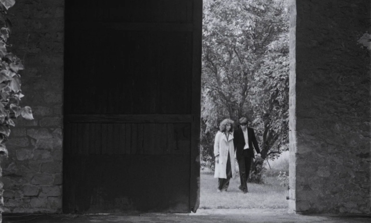 The Secret Son (1979) movie still: wide — A dark stone barn doorway frames a bright outdoor scene with trees and grass. A young man and woman in…