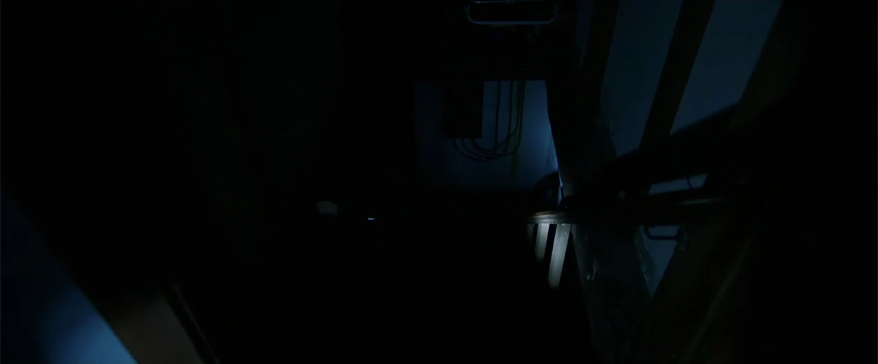 Lights Out (2016) movie still: establishing — A dark, narrow indoor staircase with visible handrails leading down into pitch blackness. An unlit or…
