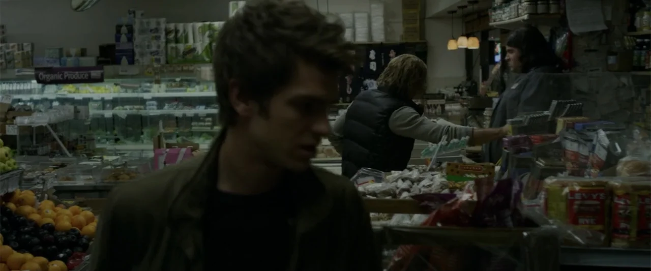 The Amazing Spider-Man (2012) movie still: medium — A grocery store interior features produce bins in the foreground and a checkout counter. A young…