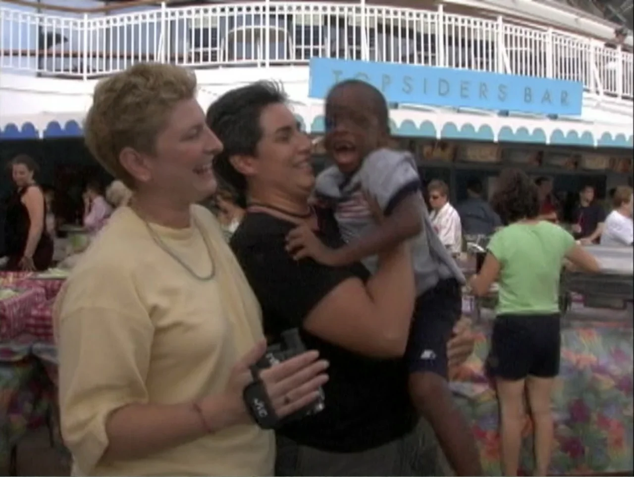 All Aboard! Rosie's Family Cruise (2006) movie still: medium — A group of people gathers on the deck of a large passenger cruise ship. A woman…