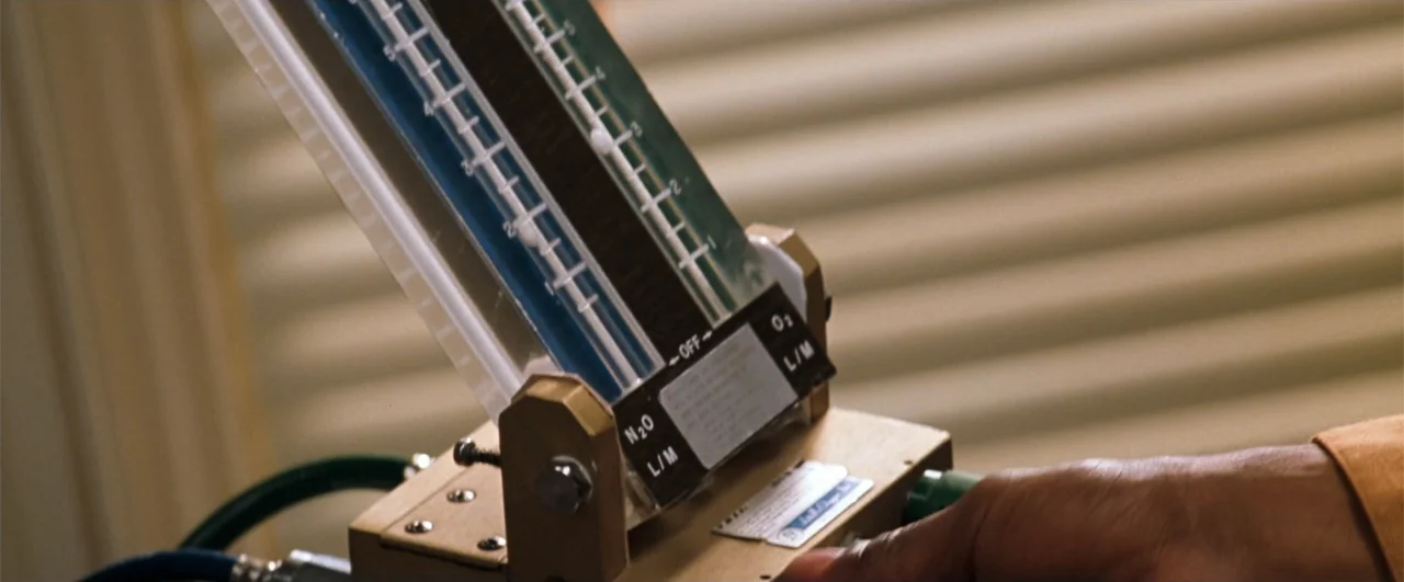 Lethal Weapon 4 (1998) movie still: closeup — A close-up of a nitrous oxide and oxygen flow meter mounted in a clinic. A hand enters the frame from…